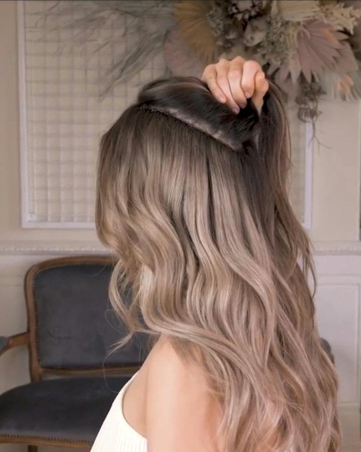 A woman with long balayage hair in a salon